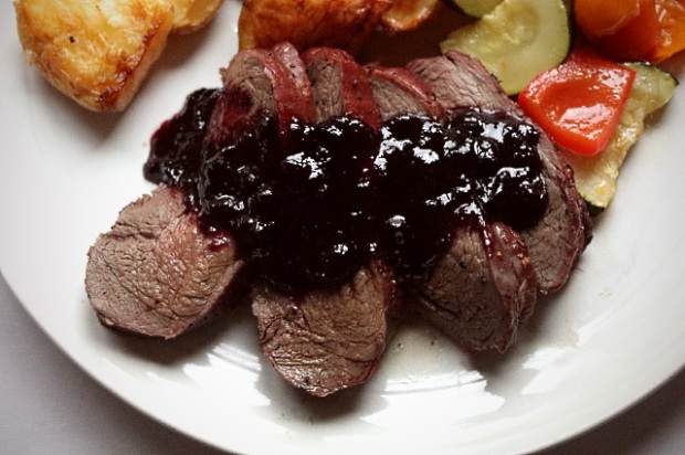 Roast venison haunch and huckleberry sauce served with vegetables